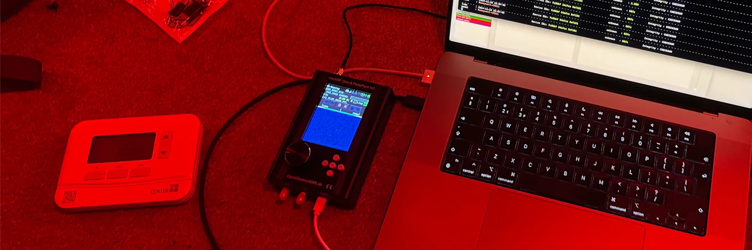 Very bright red photo of a Macbook plugged into a HackRF radio, with my thermostat sitting next to it
