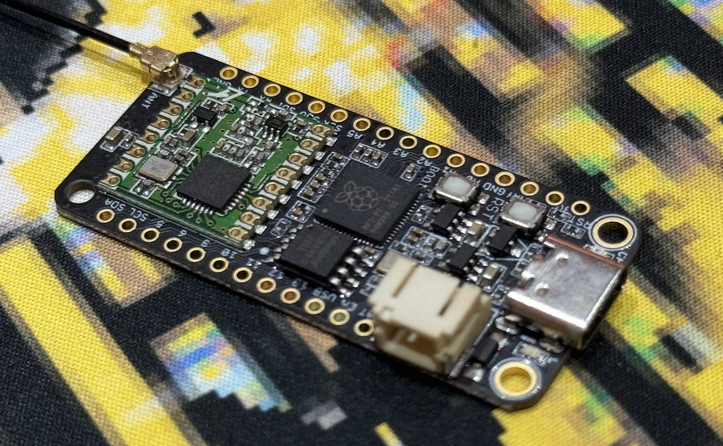 A small Challenger development board with an 868 MHz antenna, wired up on a desk.